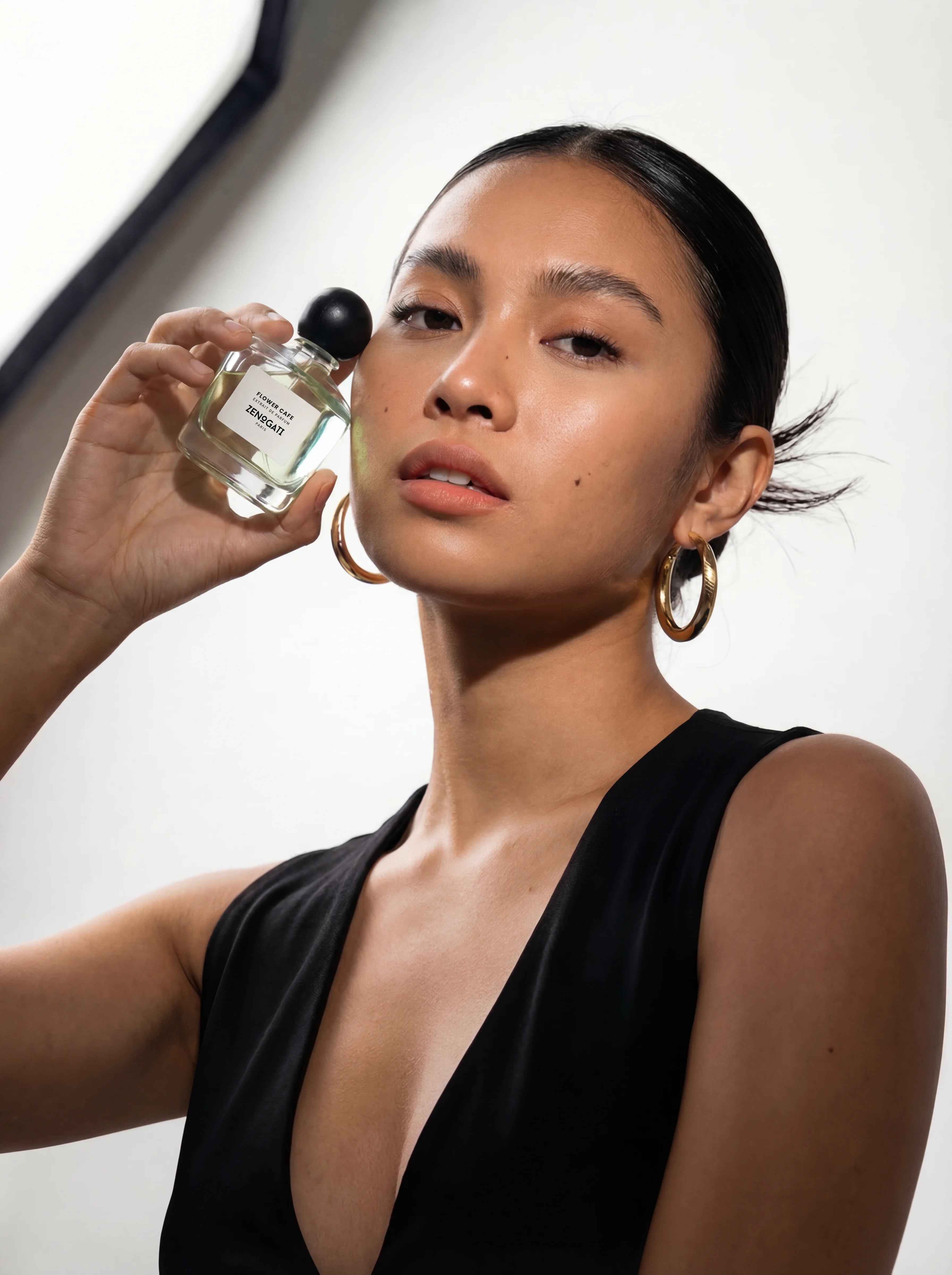 Portrait élégant d’une femme tenant le parfum Flower Café de Zenogati dans une lumière naturelle
