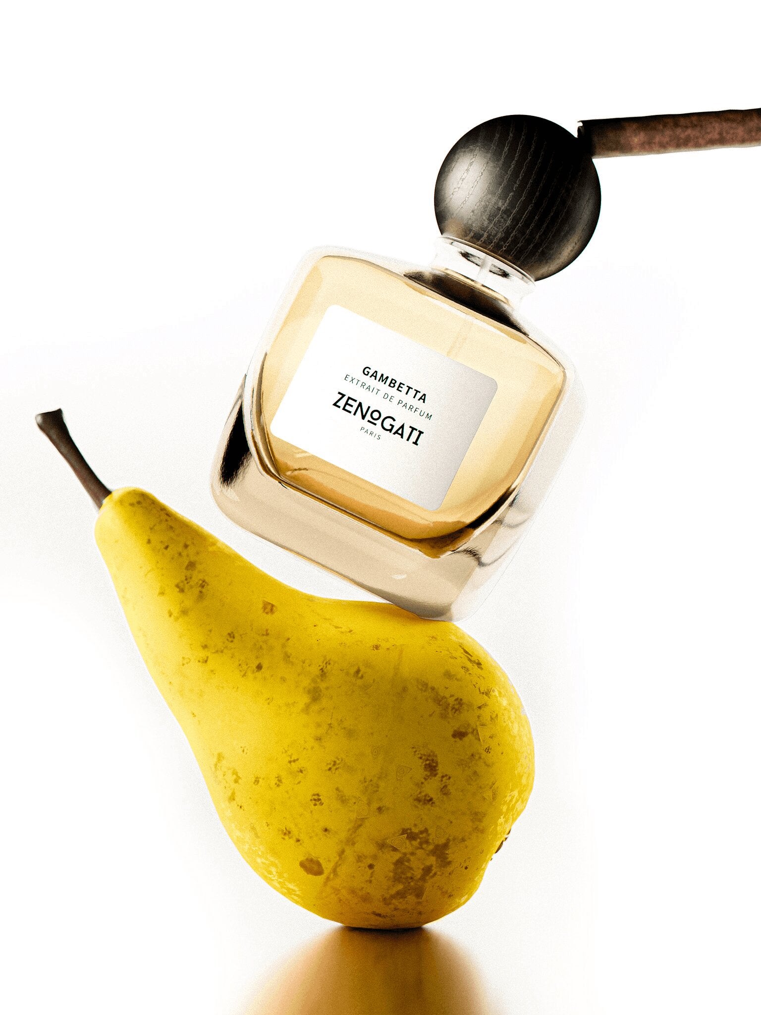 Flacon Zenogati Gambetta en équilibre sur une poire, fond blanc